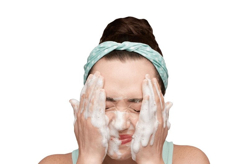 Bàn tay vỗ nhẹ nước lên mặt để rửa sạch lớp mặt nạ ngủ vào buổi sáng, thể hiện quy trình chăm sóc da