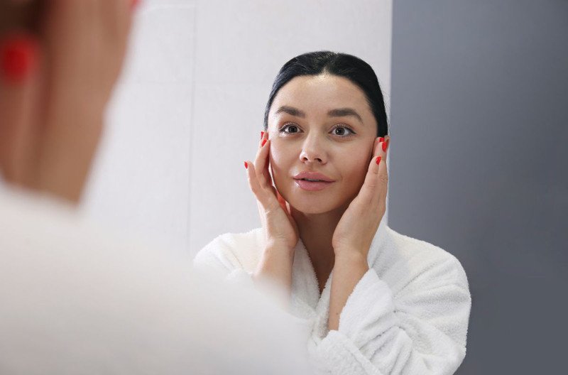 Đầu ngón tay đang nhỏ giọt serum tinh chất lên lòng bàn tay sẵn sàng cho việc thoa lên mặt
