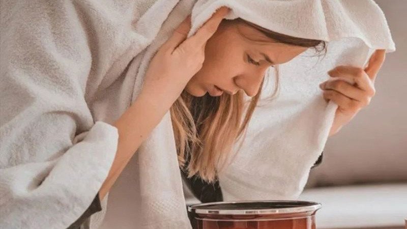 Hình ảnh một người phụ nữ đang tận hưởng buổi xông hơi mặt bằng nước nóng để làm sạch sâu da