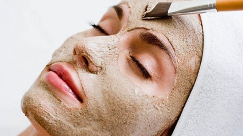 Người phụ nữ đang nhẹ nhàng thoa mặt nạ bột cám gạo lên mặt
