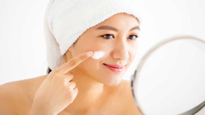 Người phụ nữ đang suy nghĩ về thời điểm tốt nhất để skincare, liệu nên skincare sau khi tắm hay trước khi đi ngủ để da hấp thụ tốt nhất.
