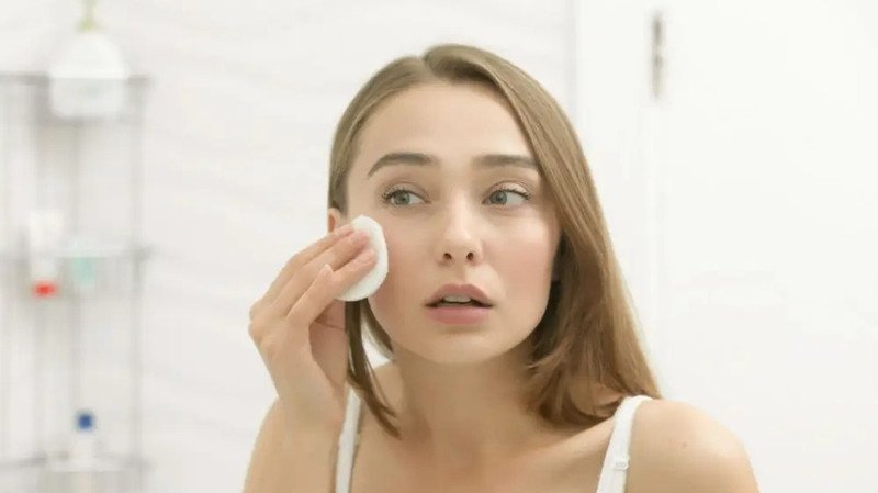 Người phụ nữ đang tẩy trang khuôn mặt, thể hiện công dụng làm sạch sâu của nước tẩy trang