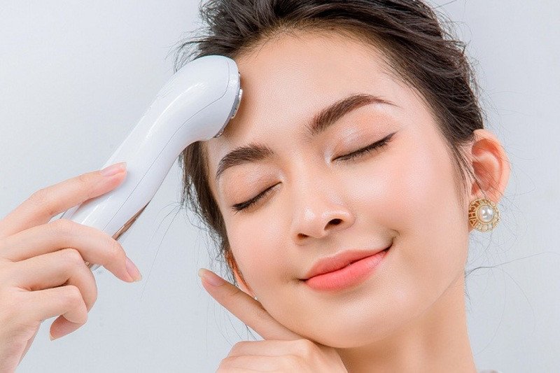 Người phụ nữ đang thực hiện cách sử dụng máy massage mặt cầm tay để làm sạch da
