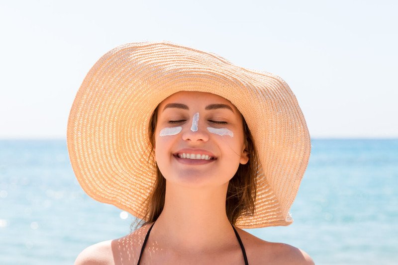 Người phụ nữ thoa kem chống nắng để bảo vệ da khỏi tác động của tia UV